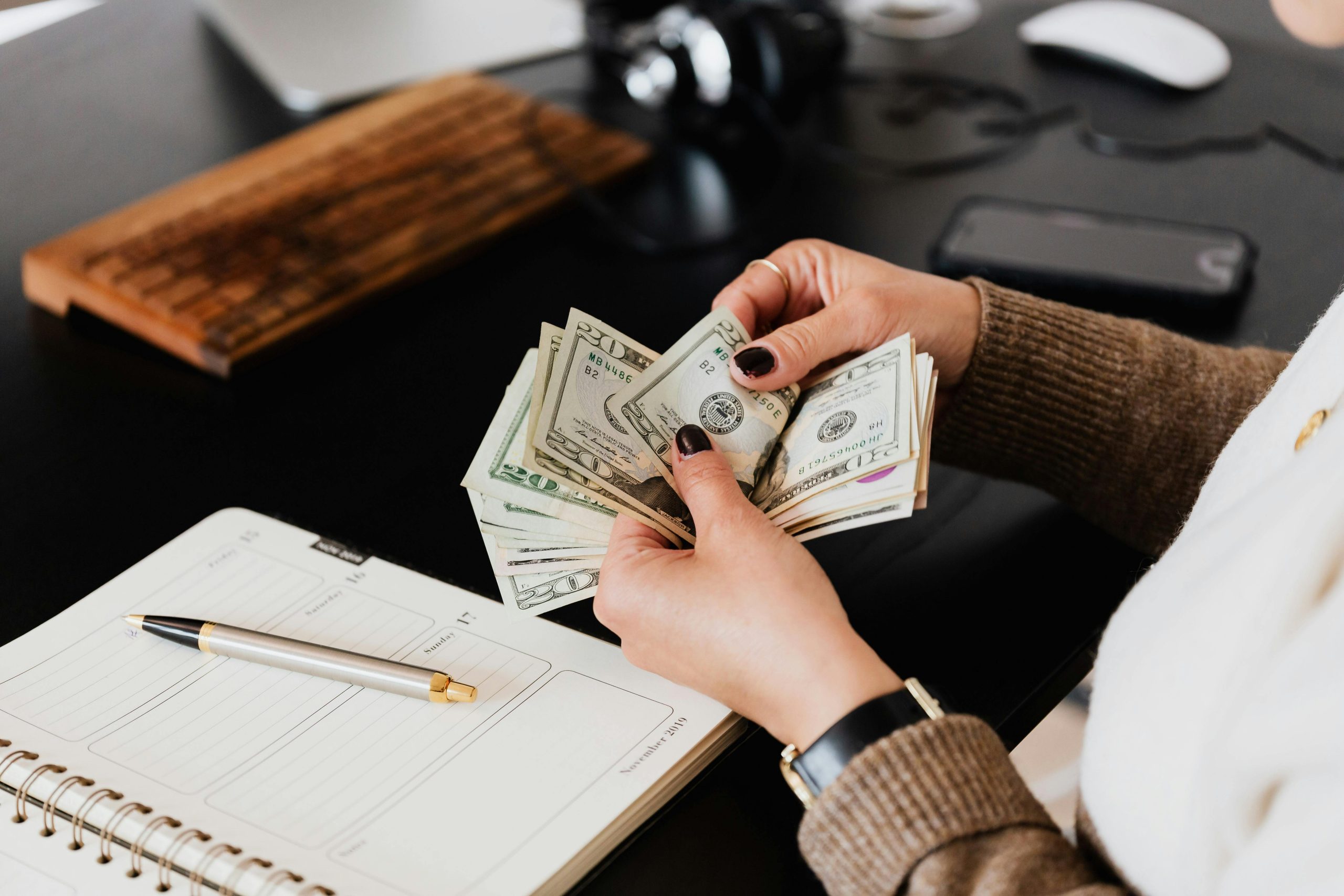 Picture of a womans hands counting cash over a desk